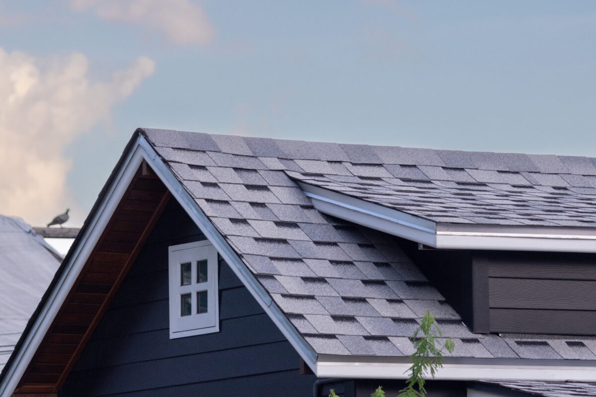 roof shingle with with garret window with the blue sky in evening. house roof. concept : buy or rent house resident.