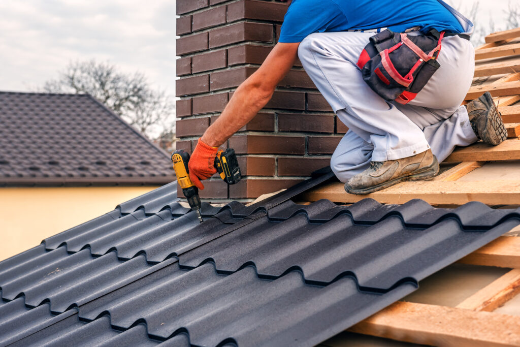 roof repair cost a professional master (roofer) with electric screwdriver covers repairs the roof near the chimney