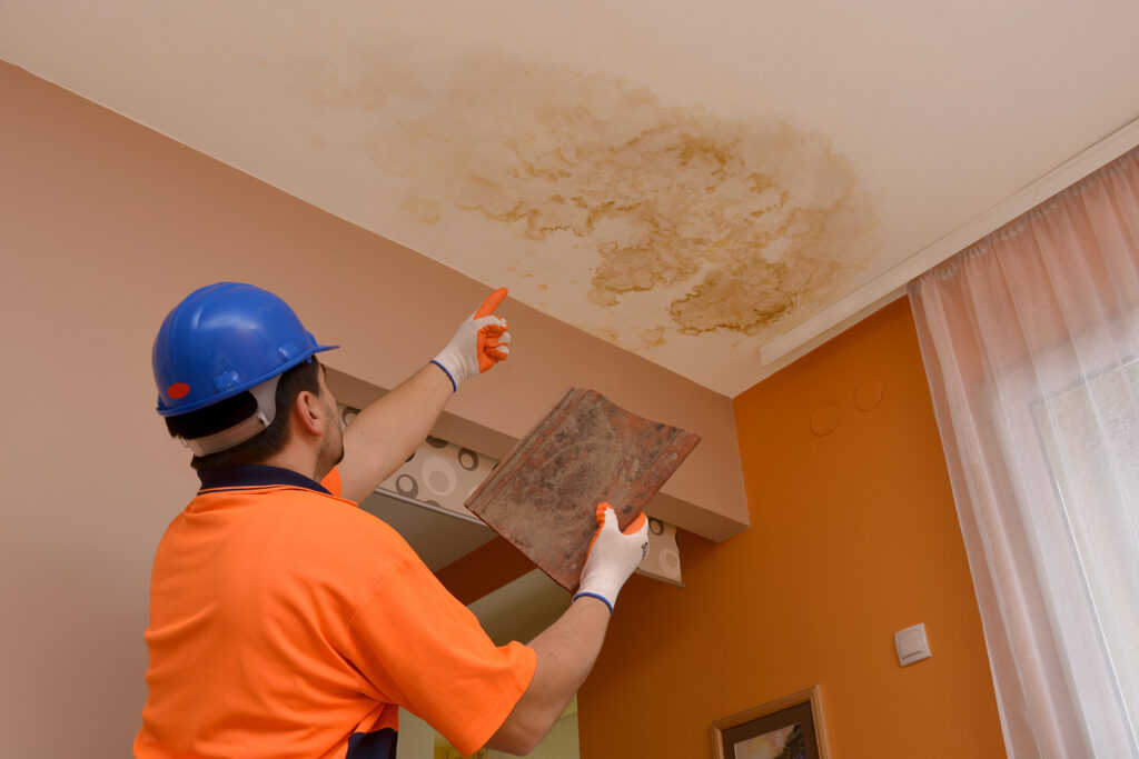 ceiling leak construction worker points to the place where the leaked water,