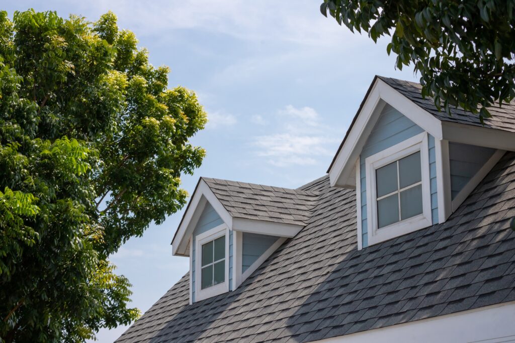 does a new roof increase home value Roof shingles with garret house on top of the house among a lot of trees. dark asphalt tiles on the roof background
