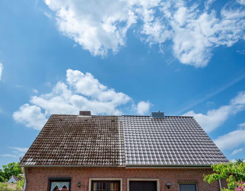 A half cleaned house roof shows the before and after effect of a roof cleaning