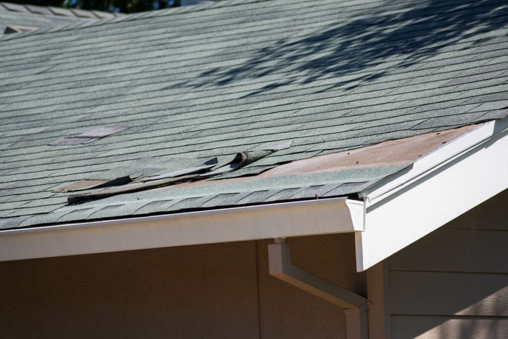 Asphalt shingle roofing on a residential home with visible damage, curled edges