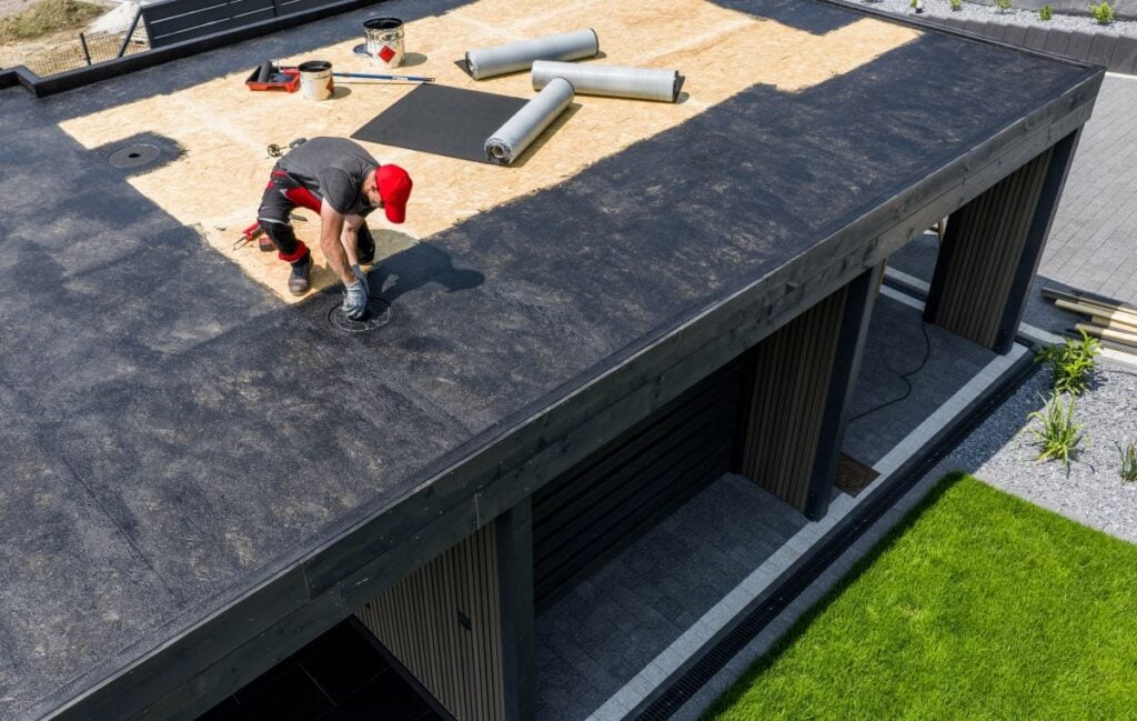 Construction Worker Applying EPDM Roofing Material on Modern House During Daytime