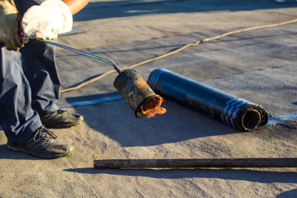 Roll roofing Installation with propane blowtorch during construction works