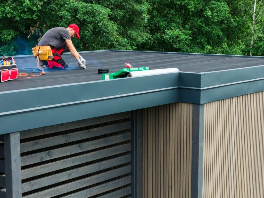 Skilled Worker Performing Maintenance on a Modern Flat Roof in Daylight